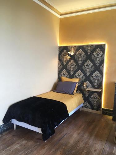 a bedroom with a bed with a black blanket on it at Les Croque-Notes, chambres et table d'hôtes in Lorignac