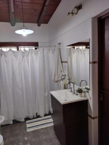 baño con lavabo y cortina de ducha blanca en CampoMora- 5 min del Centro - CONFORT - Parrilla & Pileta en San Salvador de Jujuy