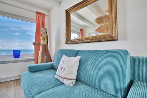 un divano blu in soggiorno con specchio di Strandallee 10 Penthouse Seaview a Haffkrug