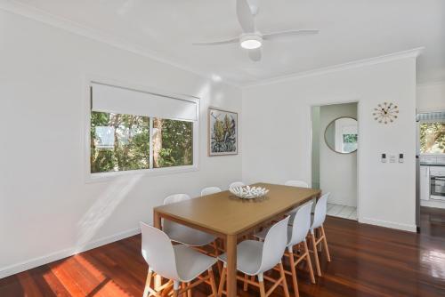 a dining room with a wooden table and white chairs at Home View 10B Yarrong in Point Lookout