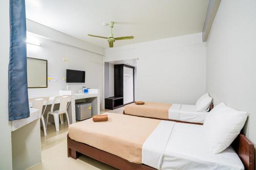 a hotel room with two beds and a table at Pasawang Hotel (โรงแรมภาสว่าง) in Hat Yai