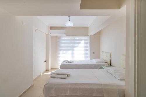 two beds in a white room with a window at Apartments Near to City Center and Beach in Marmaris