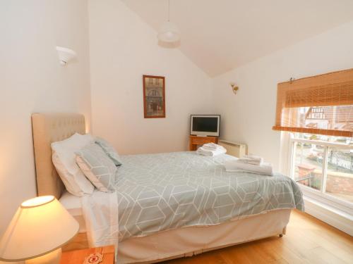 a bedroom with a bed and a lamp and a window at The Lodge at Cross Cottage in Wrexham