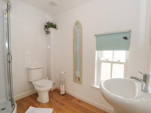 a white bathroom with a toilet and a sink at The Lodge at Cross Cottage in Wrexham