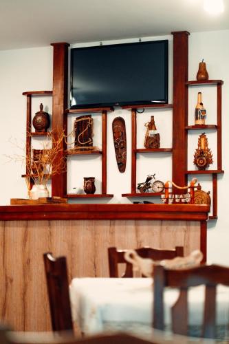 a flat screen tv on a wall with a table and chairs at Casa Cheile Dâmbovicioarei - Cabana 2 in Dîmbovicioara
