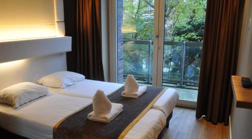 a bedroom with a bed with two pillows and a window at Hotel Mosaic City Centre in Amsterdam