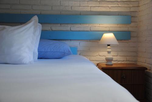 Blu Inn في بونتا دل إستي: غرفة نوم بها سرير مع اللوح الأمامي الأزرق ومصباح