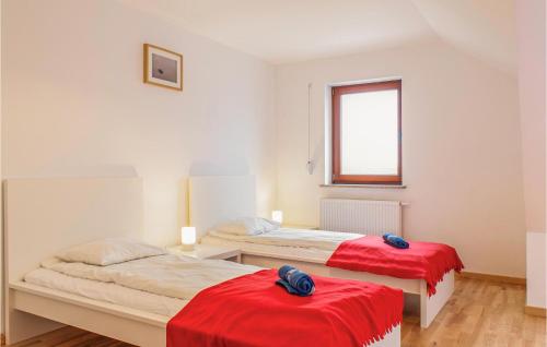 a bedroom with two beds with red sheets and a window at Stunning Home In Mielno With Wifi in Mielno
