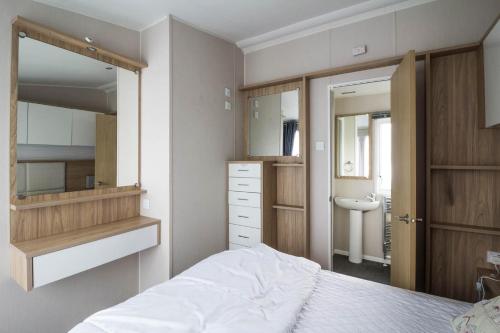 a bedroom with a bed and a sink and a mirror at Luxury Caravan At Seaview Holiday Park In Kent Ref 47034pb in Whitstable