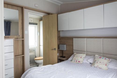 a bedroom with a white bed and a bathroom at Luxury Caravan At Seaview Holiday Park In Kent Ref 47034pb in Whitstable