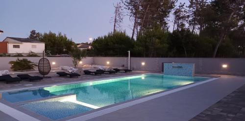 a swimming pool in a backyard with chairs around it at Apartments-Sana-2 in Vir