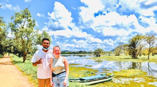 a man and a woman standing next to a river with a boat at Sigiri Liya Rest in Sigiriya
