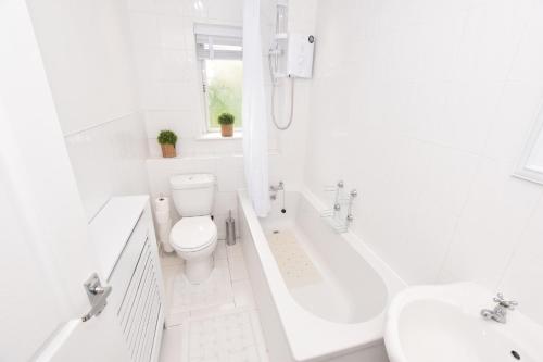 Baño blanco con aseo y lavamanos en Lovely 2 Bedroom Flat in a quiet location en Airdrie