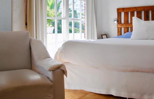 a bedroom with a bed and a chair and a window at Blu Inn in Punta del Este