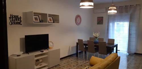 sala de estar con mesa de comedor y TV en Home Sweet Home, en Battipaglia