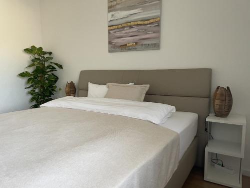 Un dormitorio con una cama blanca y una planta en Hopfenglück, en Tettnang