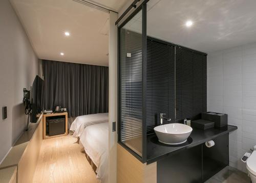 een badkamer met een wastafel en een bed bij Hotel Wolmido in Incheon
