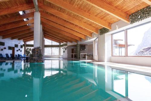 an indoor swimming pool with a wooden ceiling and a swimming pool at Lodge El Morado in Refugio Lo Valdés