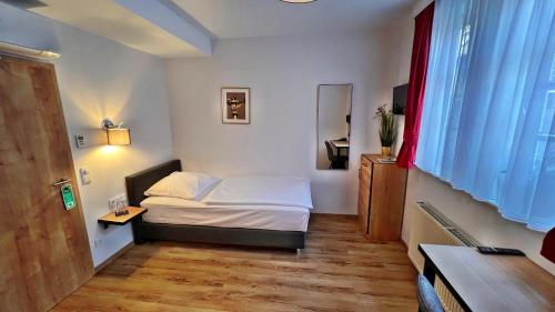 a bedroom with a bed and a desk and a window at Hotel Zu den Drei Kronen in Seligenstadt