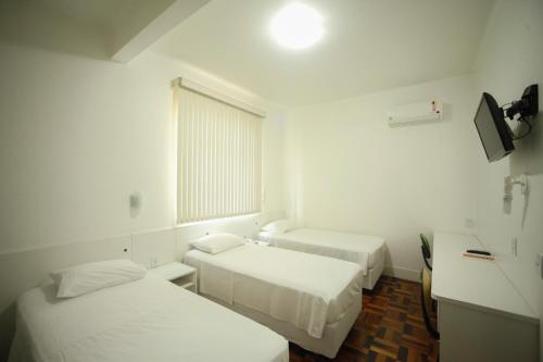 a small room with two beds and a window at Hotel Vitoria - Itajaí in Itajaí