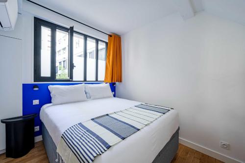 um pequeno quarto com uma cama e uma janela em Magnifique appartement 2BR/4P - Marais/Bastille em Paris