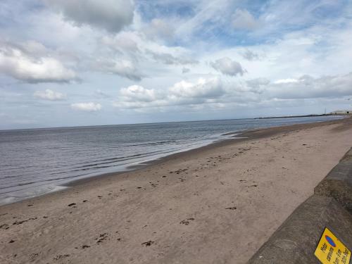 a beach with the ocean and a cloudy sky at Maze Great Escape in Ayr