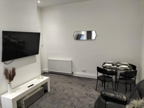 sala de estar con mesa y TV en la pared en Maze Great Escape en Ayr