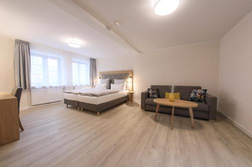 a bedroom with a bed and a couch and a table at 247 Selfcheckin Pferdemarkt in Leer