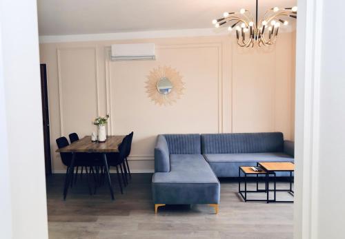 een woonkamer met een blauwe bank en een tafel bij Miku Apartment - Unique 3 Bedroom At Olympic Residence in Tirana