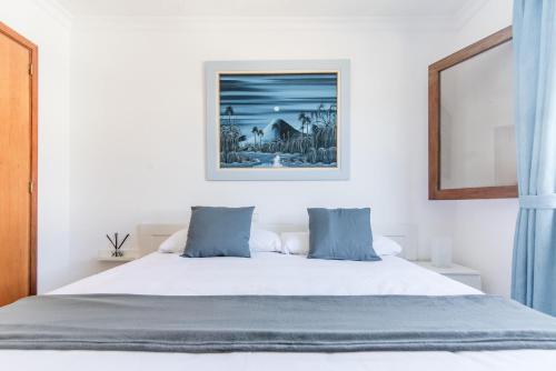 une chambre avec un lit blanc avec des oreillers bleus dans l'établissement Home2Book Puerto Rico Pool & Sun Apartment, à Puerto Rico