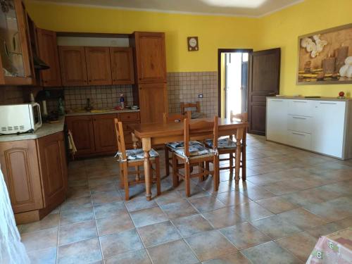 uma cozinha com uma mesa e cadeiras de madeira e uma cozinha com paredes amarelas em Casa Antonia em Tempio Pausania