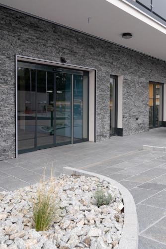 an office building with glass doors and a stone courtyard at Hotel Traunfall in Viecht