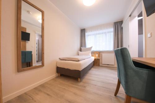 a room with a bed and a desk and a mirror at 247 Selfcheckin Pferdemarkt in Leer