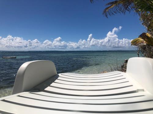 a white bench sitting on the beach near the water at Be On The Beach in Sainte-Anne