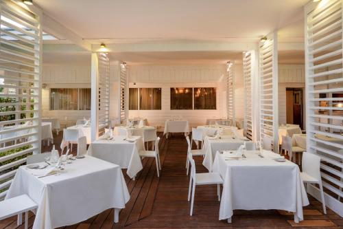 a restaurant with white tables and chairs and windows at Viva Fortuna Beach by Wyndham, A Trademark All Inclusive in Freeport