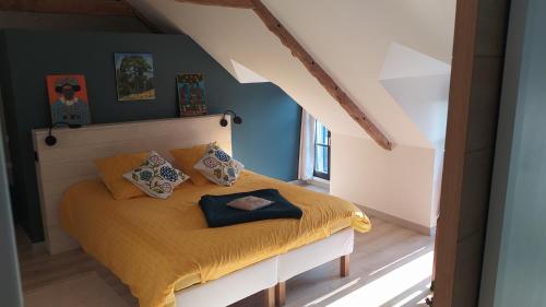 una camera da letto con letto, lenzuola e cuscini gialli di Ker Anahid - L'Atelier a Pleslin-Trigavou