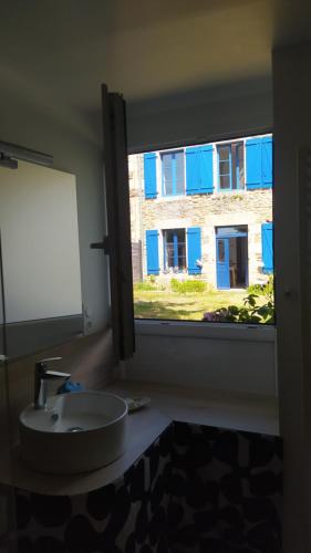 bagno con lavandino e finestra con edificio di Ker Anahid - L'Atelier a Pleslin-Trigavou