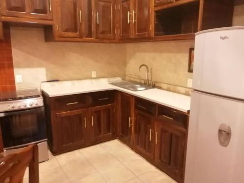 a kitchen with wooden cabinets and a white refrigerator at Casa Maribel Lugar para descansar en ixtapa in Ixtapa