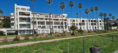 a white building with palm trees in front of it at Point Village Accommodation - Santos 40 in Mossel Bay