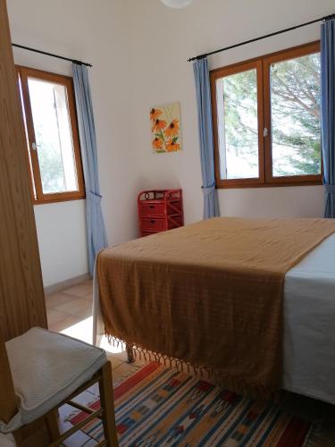- une chambre avec un lit, 2 fenêtres et une chaise dans l'établissement Les romarins, à Saint-Jean-de-Minervois