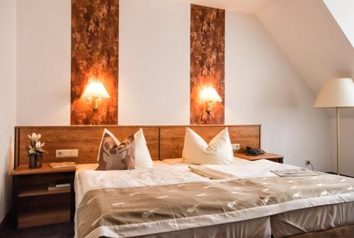 um quarto com uma cama e duas lâmpadas na parede em Hotel & Restaurant Zum Hirsch em Römhild