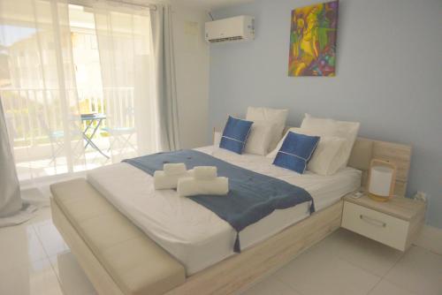 1 dormitorio con 1 cama grande con almohadas azules en L'oasis de Saint-François, studio An bel ti koté en Saint-François