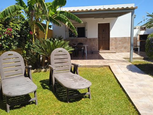 dos sillas sentadas en el césped frente a una casa en Casa vistas al mar, en El Palmar
