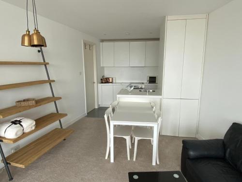a living room with a white table and a kitchen at Rotunda - New Street, City Centre, Birmingham in Birmingham