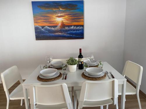 a white dining room table with white chairs and a painting at Apartamento Vista Altillo in Almuñécar