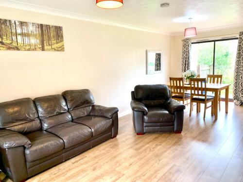 a living room with a leather couch and a table and chairs at Dada House in Glasgow