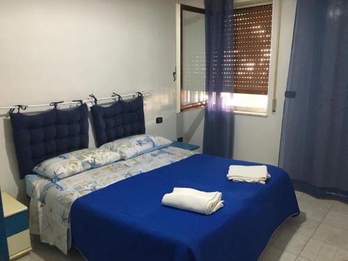 a bedroom with a blue bed with towels on it at Residence La Quiete in Taureana
