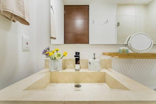 a bathroom with a sink with flowers and a mirror at ☆Brand new 2BR PH by CASA PARAISO☆ in Cancún