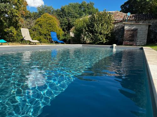 una piscina con sillas azules en un patio en Gîte loustalneve, en Bourg-de-Visa