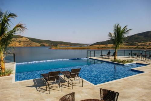 - une piscine avec des chaises et une masse d'eau dans l'établissement Pousada Enseada da Ilha, à Capitólio